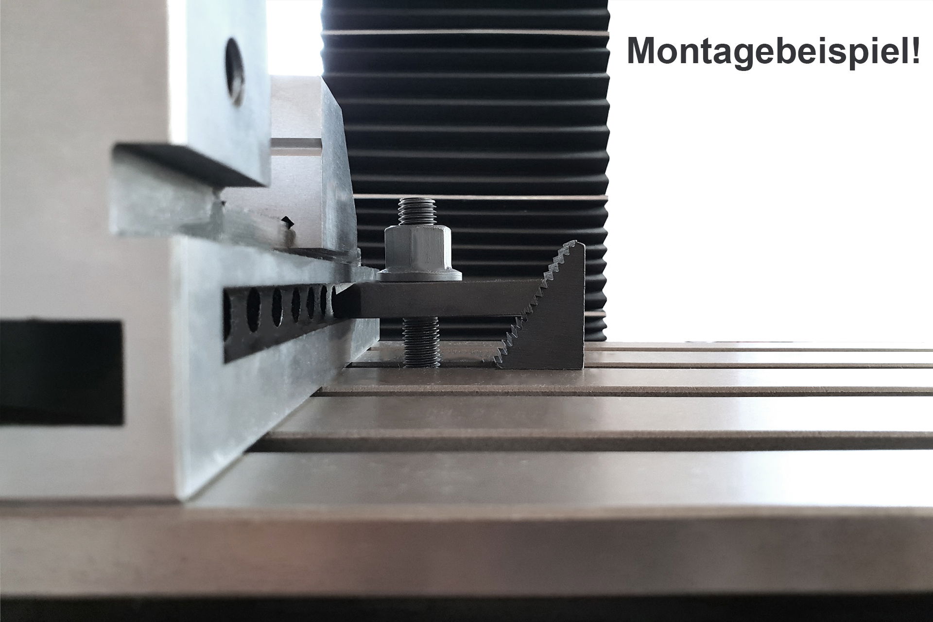 Nahaufnahme einer Spannpratze. Ein Werkstück wird mit Stufenblock, Gewindestange und Bundmutter auf einer Werkbank befestigt. Montagebeispiel.